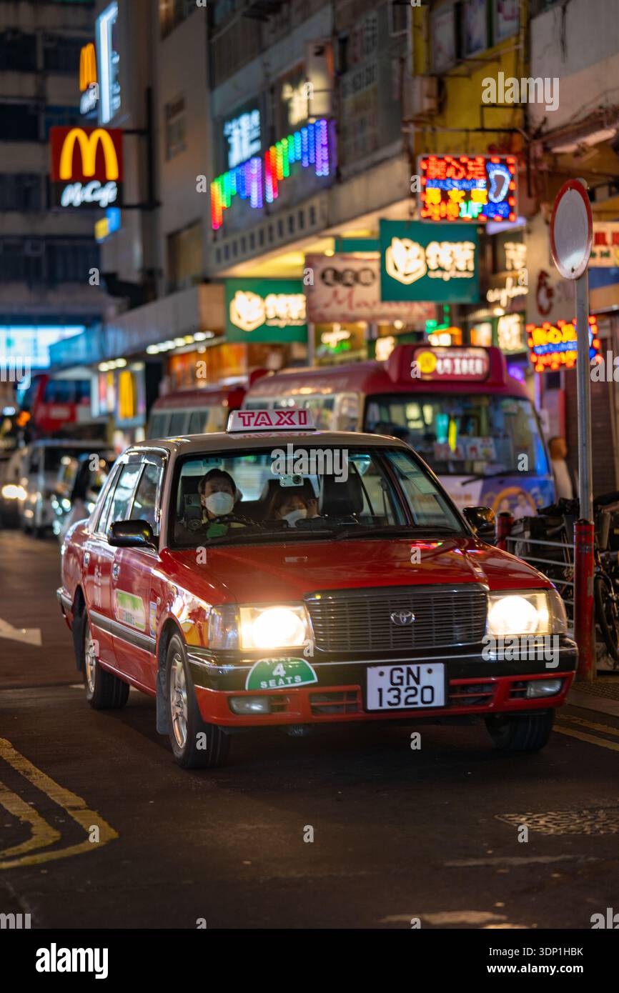 Ein ikonisches rotes Toyota Crown Comfort Taxi in Hongkong bei Nacht. Diese Fahrzeuge wurden 2026 aufgenommen und repräsentieren das Erbe der Stadt. Stockfoto