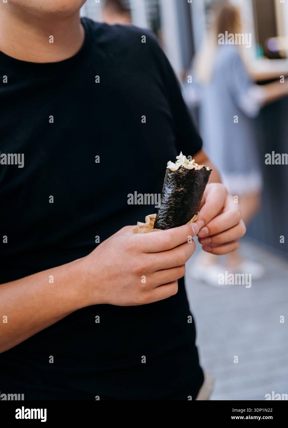 Nahaufnahme einer Person, die im Freien Sushi-Handrollen-Street Food-Snack hält Stockfoto