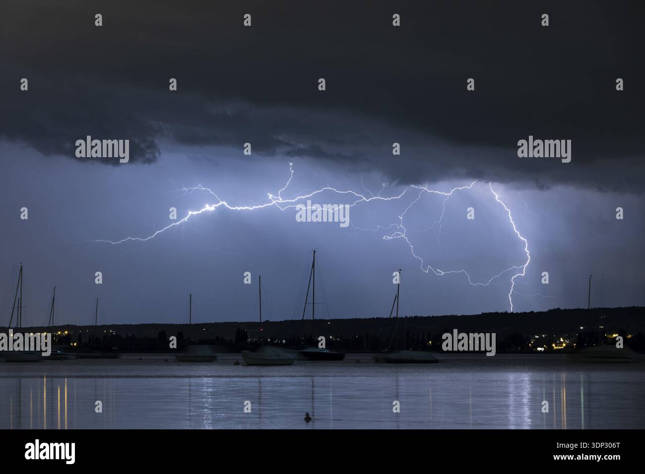 Nächtlicher Blick auf einen Sturm über einem See, Blitze erhellen den Himmel mit Silhouettenbooten, Seegarten, Allensbach, Bodensee, Baden-Wuerttemberg, Ge Stockfoto