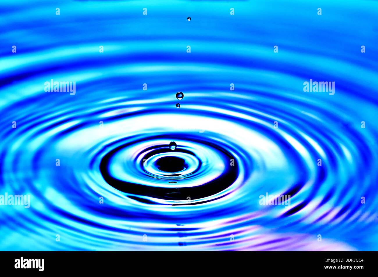 Ein Wassertropfen, der ins Wasser fällt und Wellen erzeugt Stockfoto
