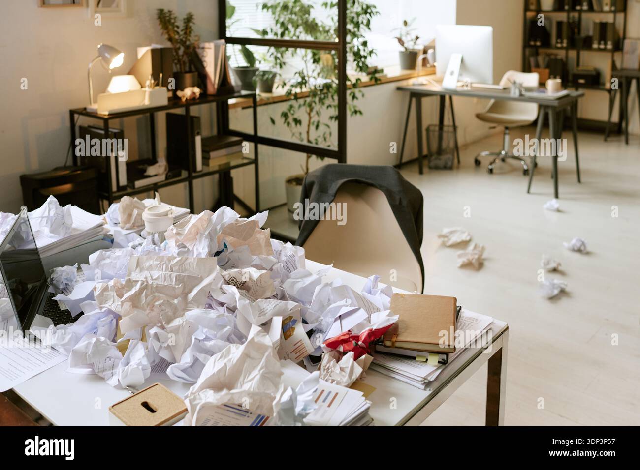 Unordentlicher Schreibtisch mit zerknittertem Papier, das den Stress am Arbeitsplatz darstellt Stockfoto