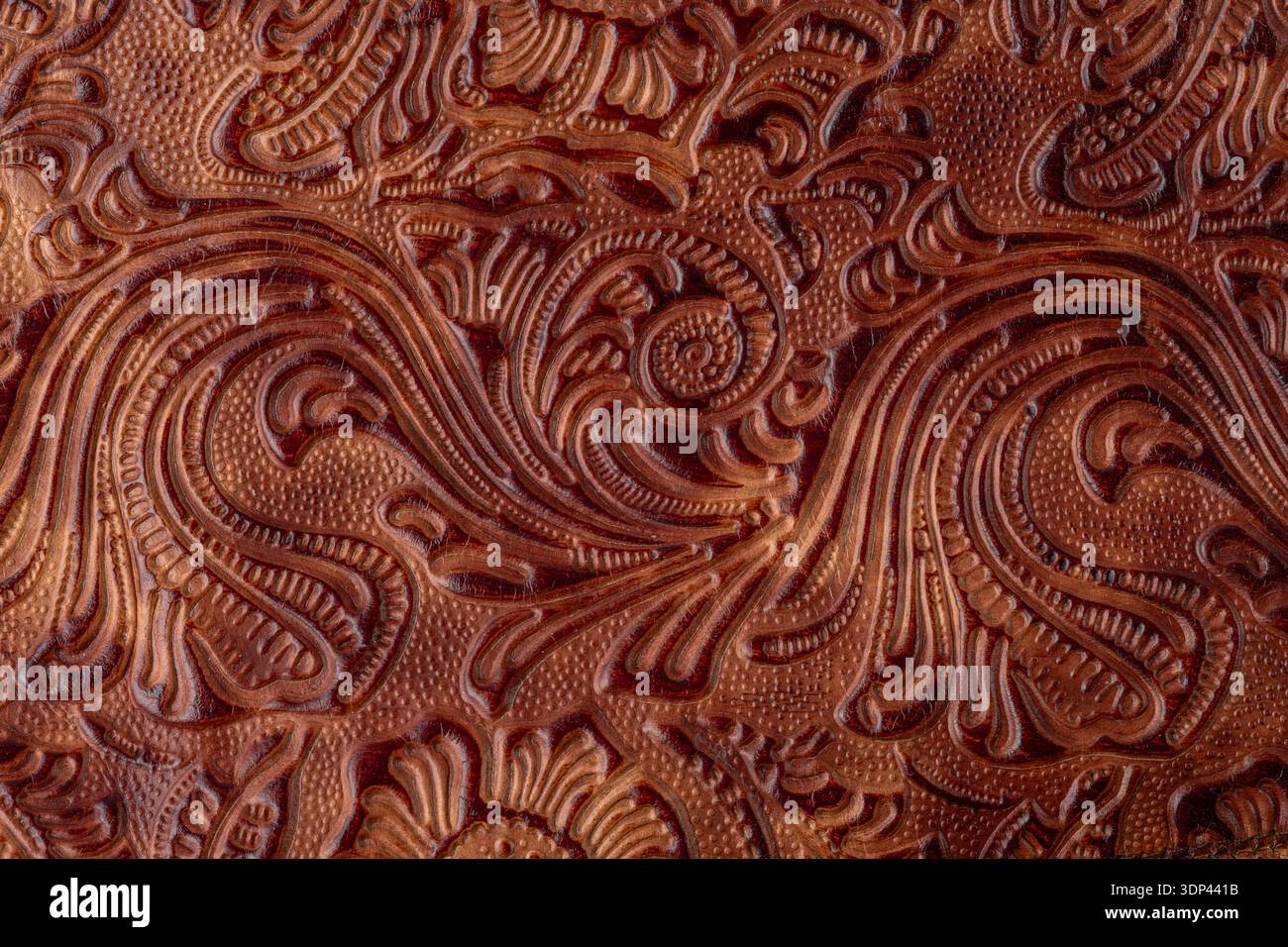 Dunkelbraunes, altes, rissiges Leder mit Blumenmuster. Probe von rauem Leder mit Ornament. Vintage-Style. Retro-Lederhintergrund. Stockfoto