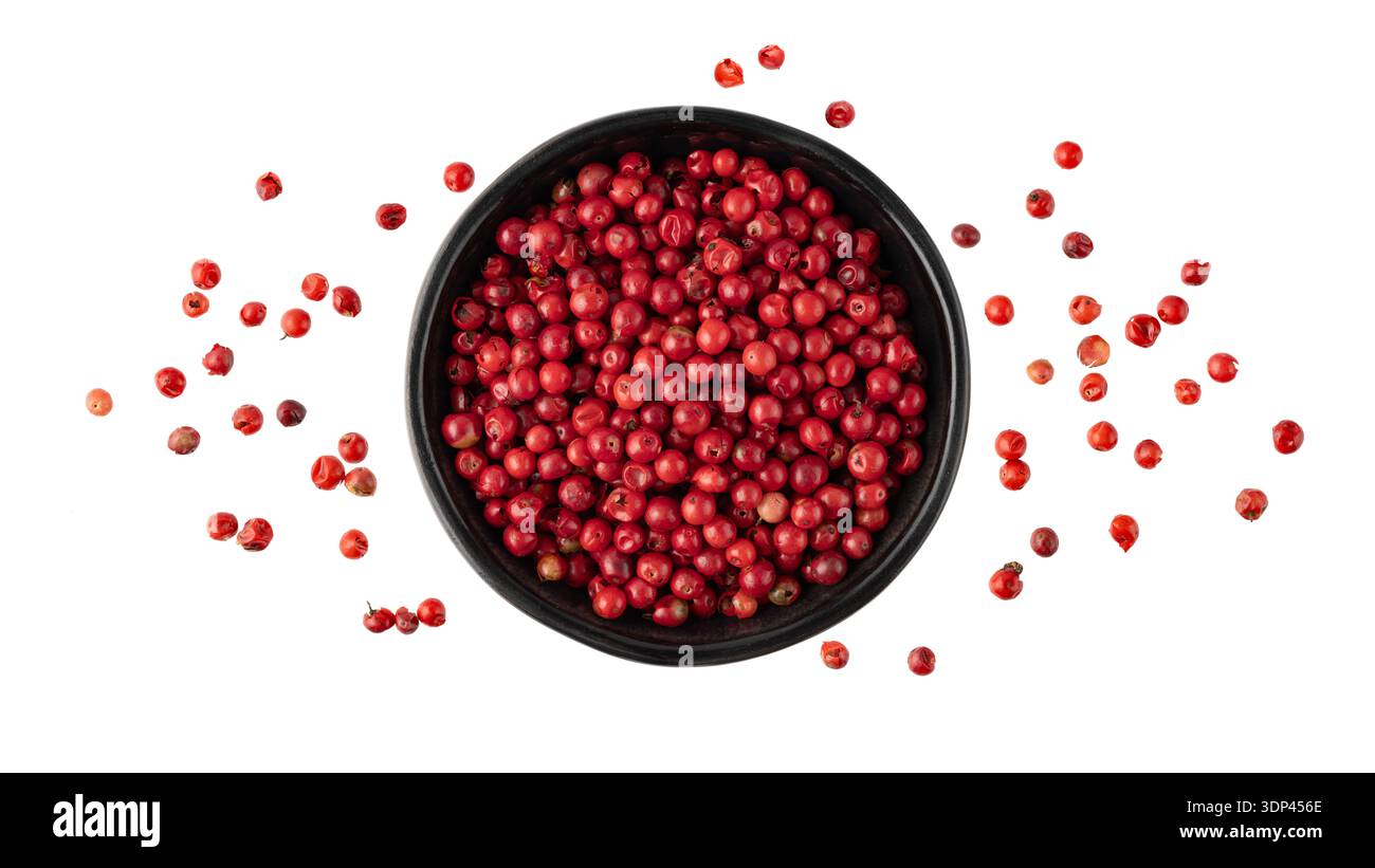 Rosa Pfeffer Pfefferbeere in schwarzer Schüssel, die isoliert auf weißem Hintergrund fliegt. Aromatisch-würzige Zutat für die Küche. Gewürzkarte. Stockfoto