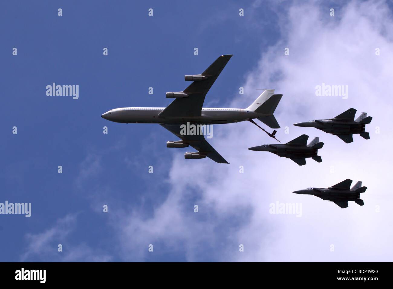 Ein großes militärisches Tankflugzeug betankt mit drei Kampfjets in Formation gegen einen blauen Himmel mit Wolken. Luftfahrt-Display Stockfoto