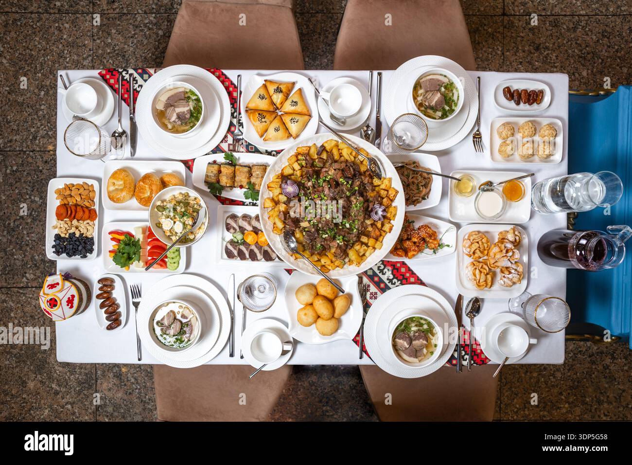 Ein sorgfältig arrangiertes Bankett mit Samosas, Plov und diversen Beilagen, perfekt für die Veranstaltungsplanung. Stockfoto