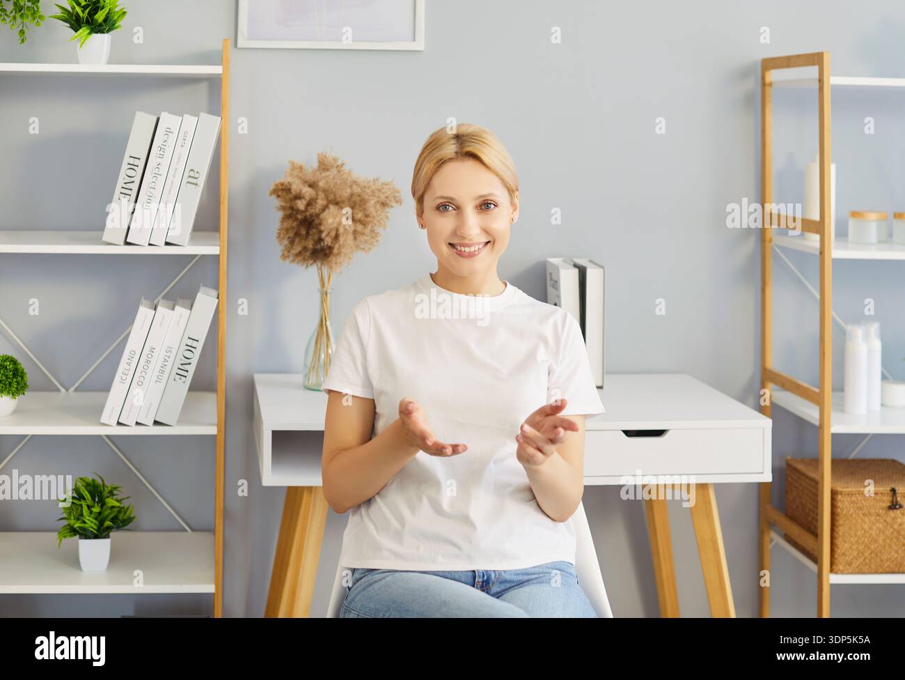 Lächelnde Frau erklärt sich mit Gesten während des Online-Videochat im Home Office Stockfoto