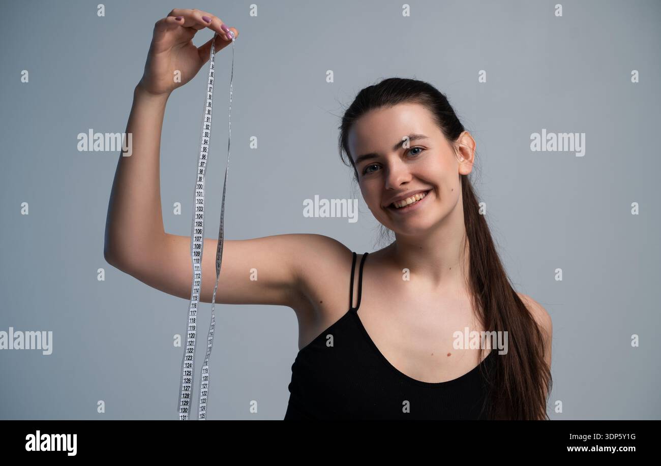 Glückliche junge Frau, die lächelt und Maßband hält Stockfoto
