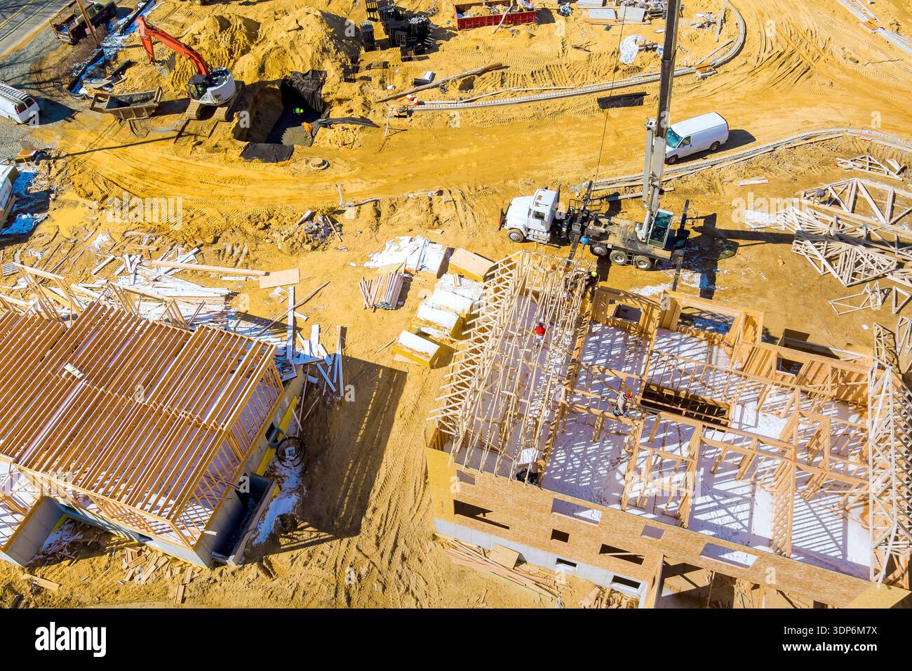 Die Arbeiter sind mit dem Bau neuer Trägerkonstruktionen auf der Baustelle mit LKW-Kränen beschäftigt Stockfoto