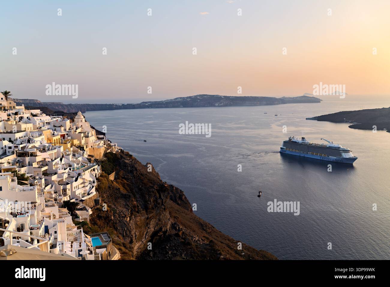 Das Kreuzfahrtschiff Odyssey of the Seas segelt bei Sonnenuntergang an den berühmten weißen Gebäuden an den Klippen von Santorin, Griechenland, vorbei und bietet einen atemberaubenden Blick auf die Touris Stockfoto