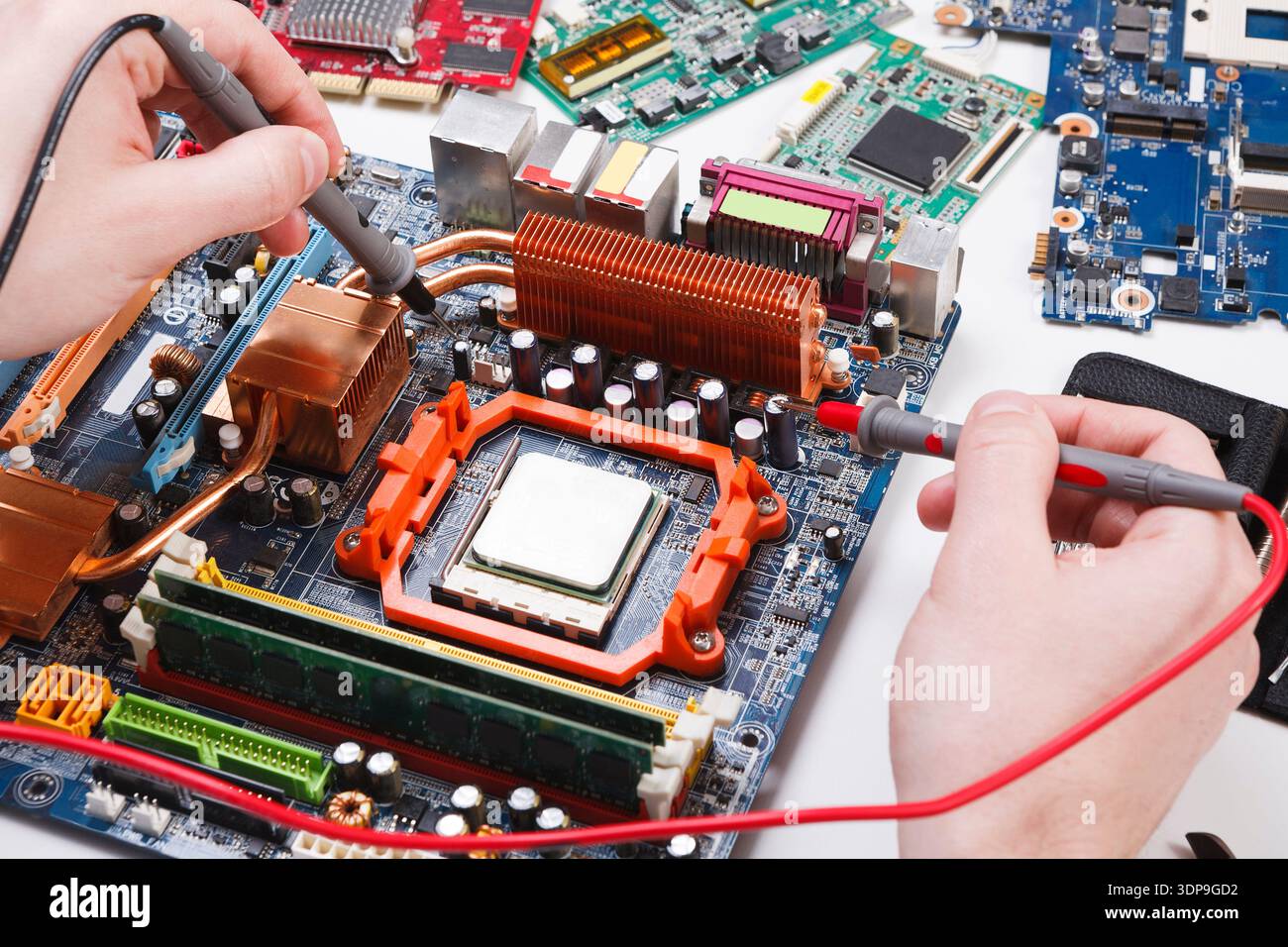 Ingenieur überprüft die Hauptplatine mit einem Multimeter Stockfoto
