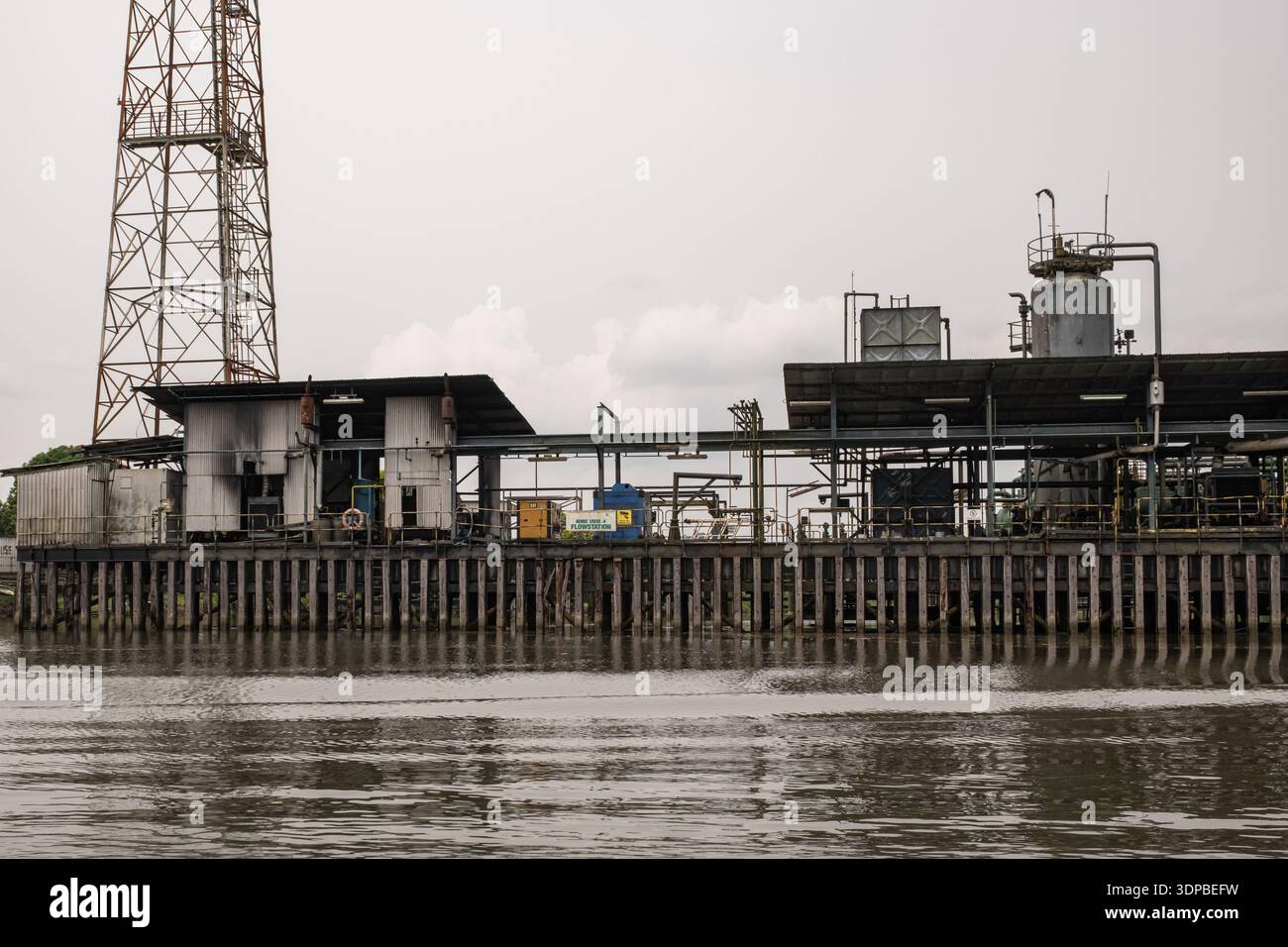 Öl- und Gasflussstation auf Holzsteg entlang des Niger Delta Creek mit Pipelines und Verarbeitungsanlagen, industrielle Energieinfrastruktur, Nigeria. Stockfoto