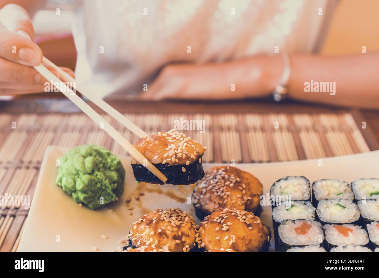 Frau mit asiatischen Stäbchen isst Sushi in Street Cafe Stockfoto