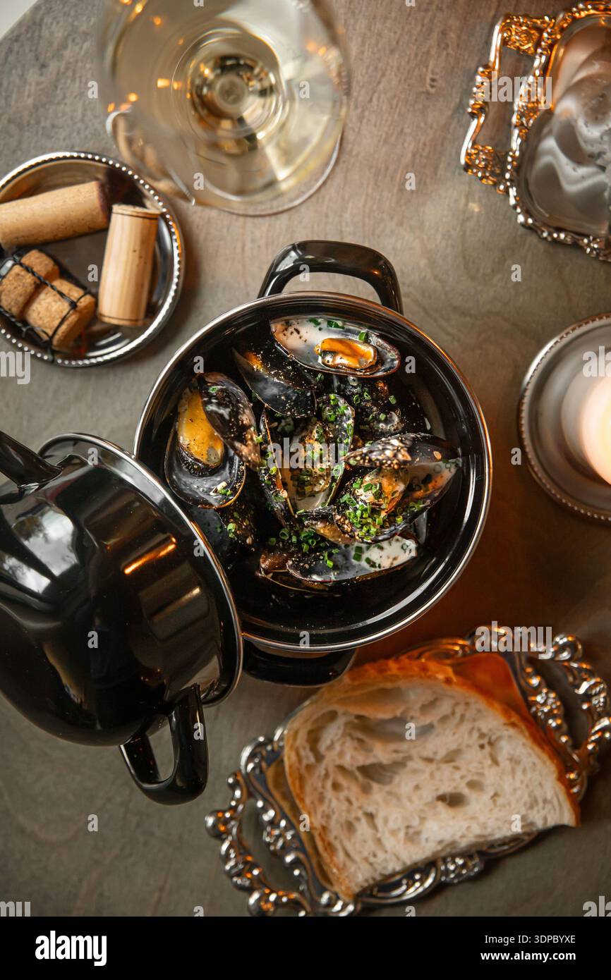 Gedämpfte Muscheln in Schwarztopf mit Brot Stockfoto
