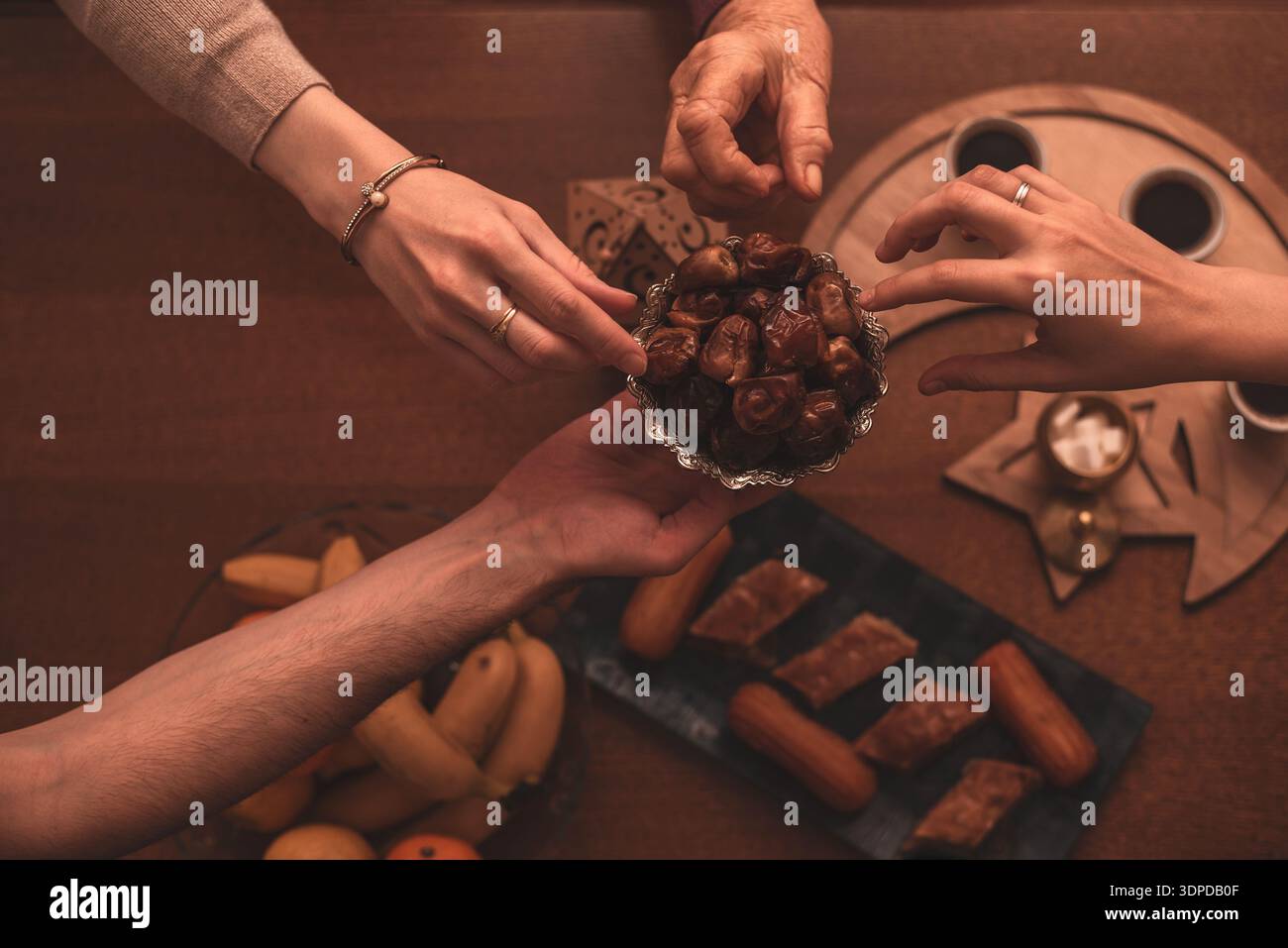 Daten während der Ramadan-Feier aus nächster Nähe von Familienmitgliedern, die während des Iftar-Essens traditionelle Speisen genießen Stockfoto