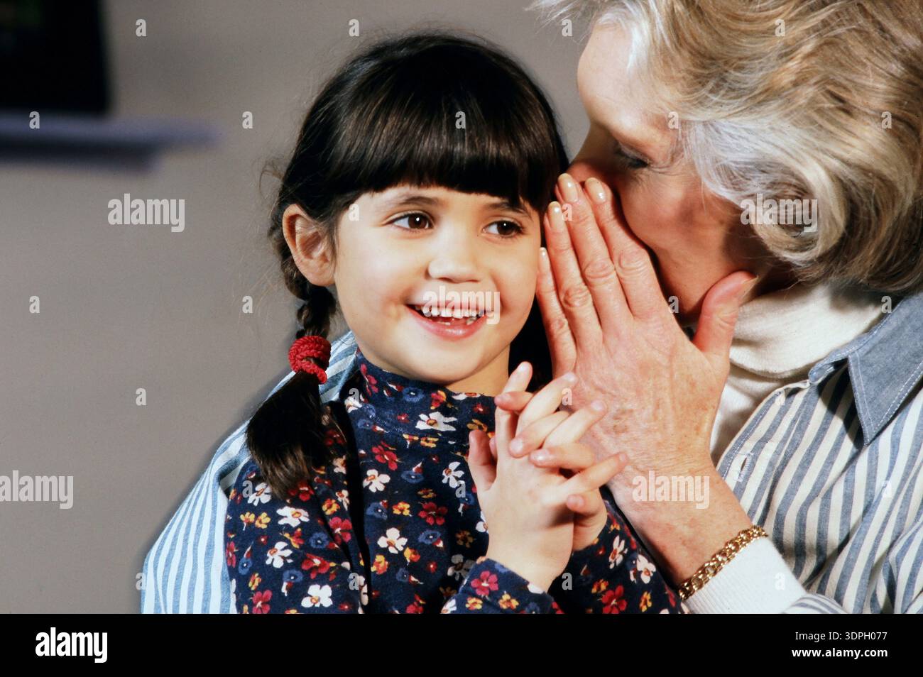Eine Großmutter und Enkelin teilen ein Geheimnis in einem glücklichen Moment Stockfoto
