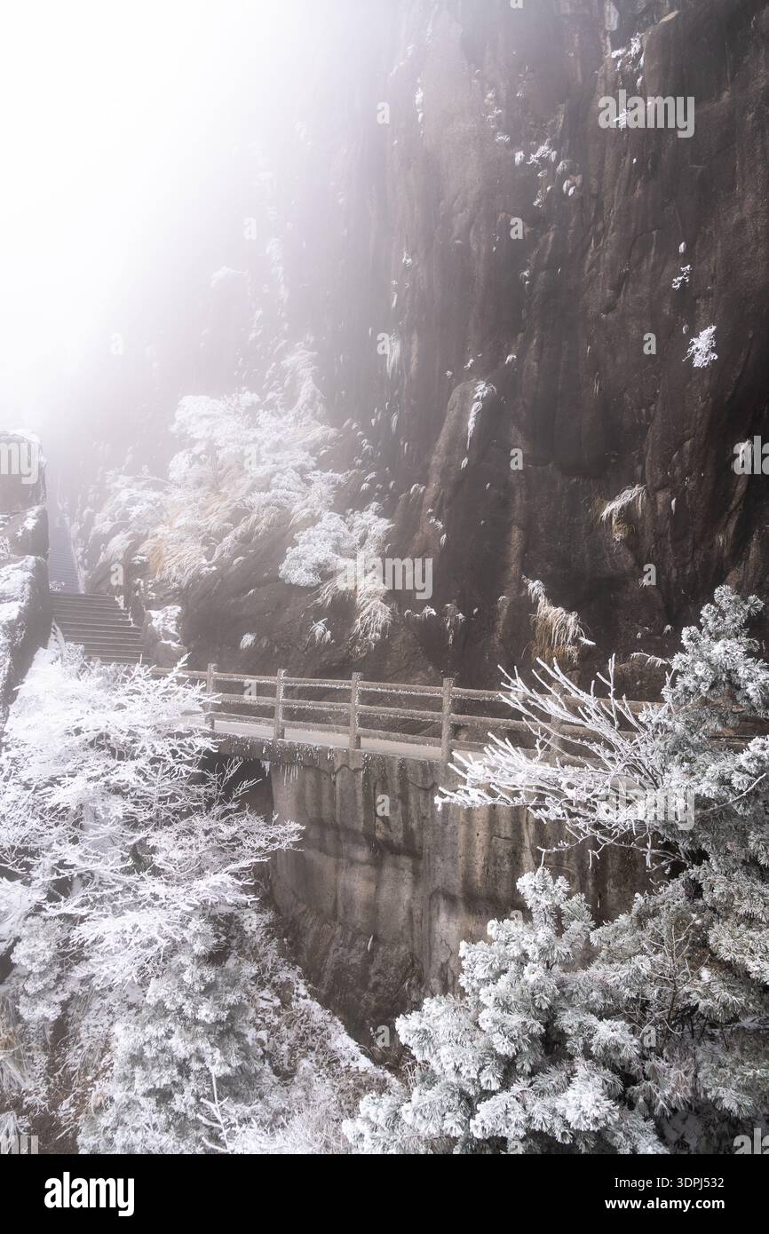 Huangshan, China: Wanderweg an der Klippe in der gefrorenen Landschaft des Gelben Berges in Mount Huangshan in China im Winter Stockfoto