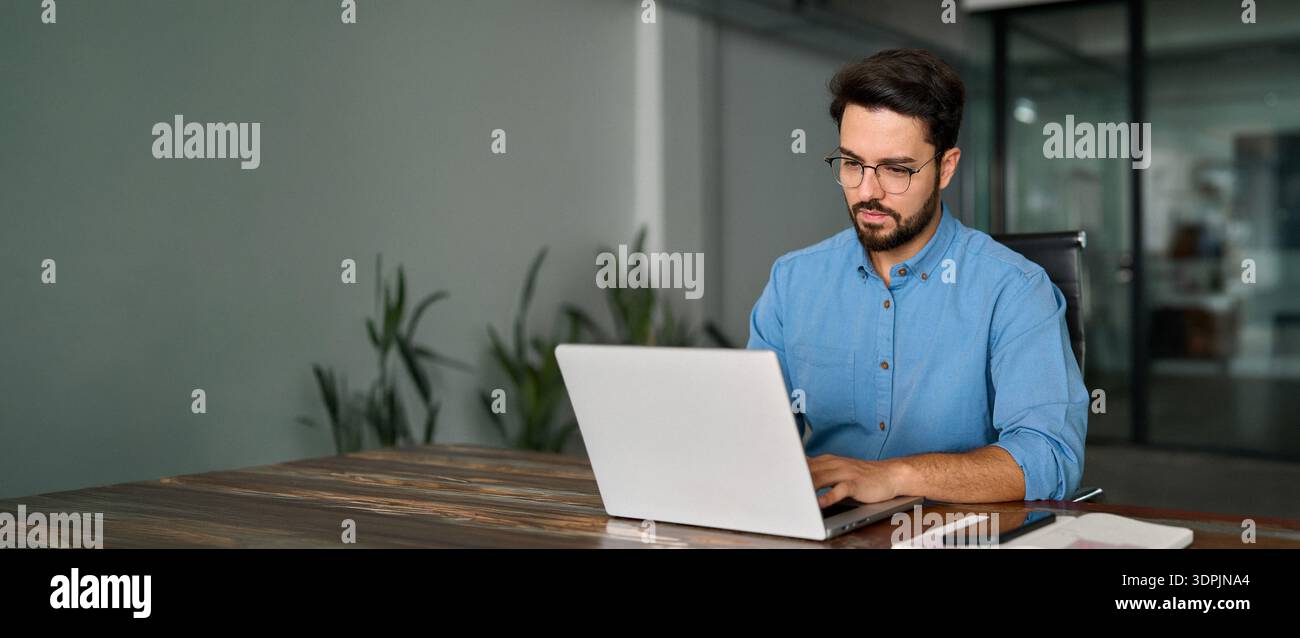 Geschäftiger Geschäftsmann mit Laptop, der im Büro arbeitet. Stockfoto