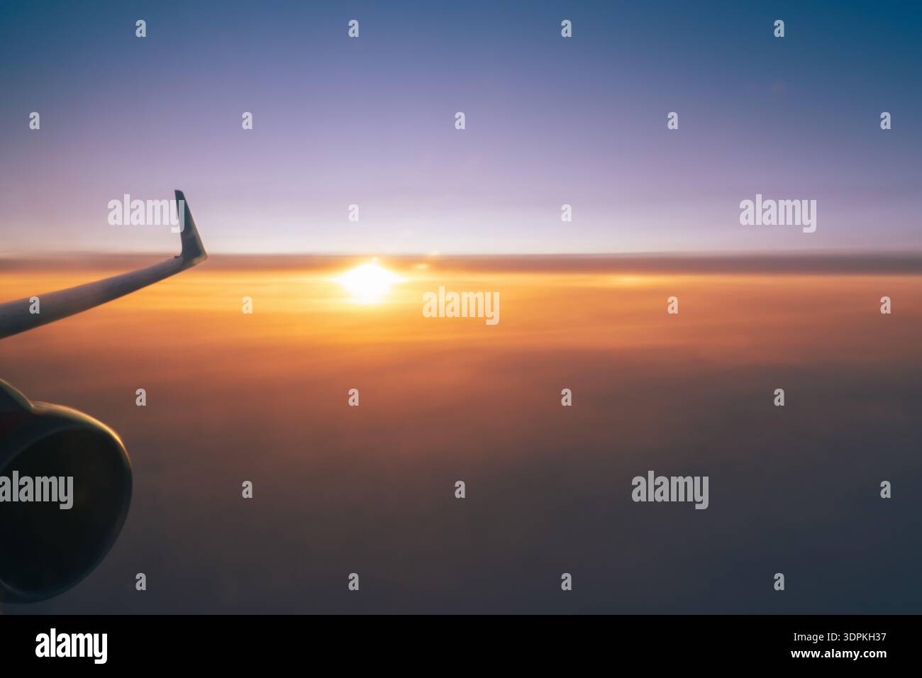 Ein fliegendes Flugzeug über einem orangefarbenen Sonnenuntergangshimmel, ein Flügel und eine Turbine aus der Nähe. Der konzeptionelle Hintergrund der Kopierraumflugreise Stockfoto