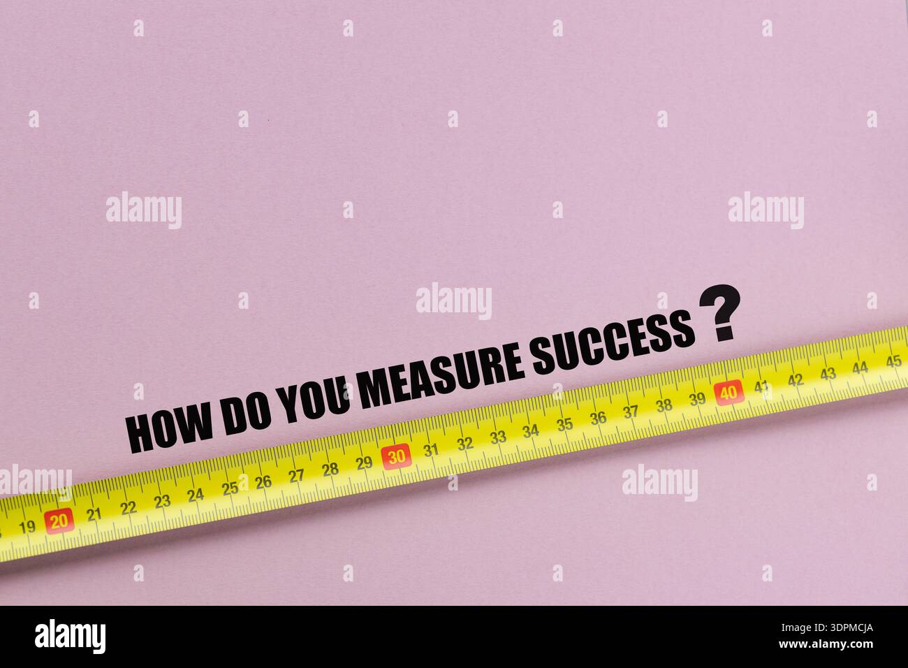 Wie messen Sie den Erfolg? Ein Slogan auf rosafarbenem Hintergrund neben einem Maßband für den Erfolg. Geschäfts- und Finanzkonzept. Kopierbereich Stockfoto