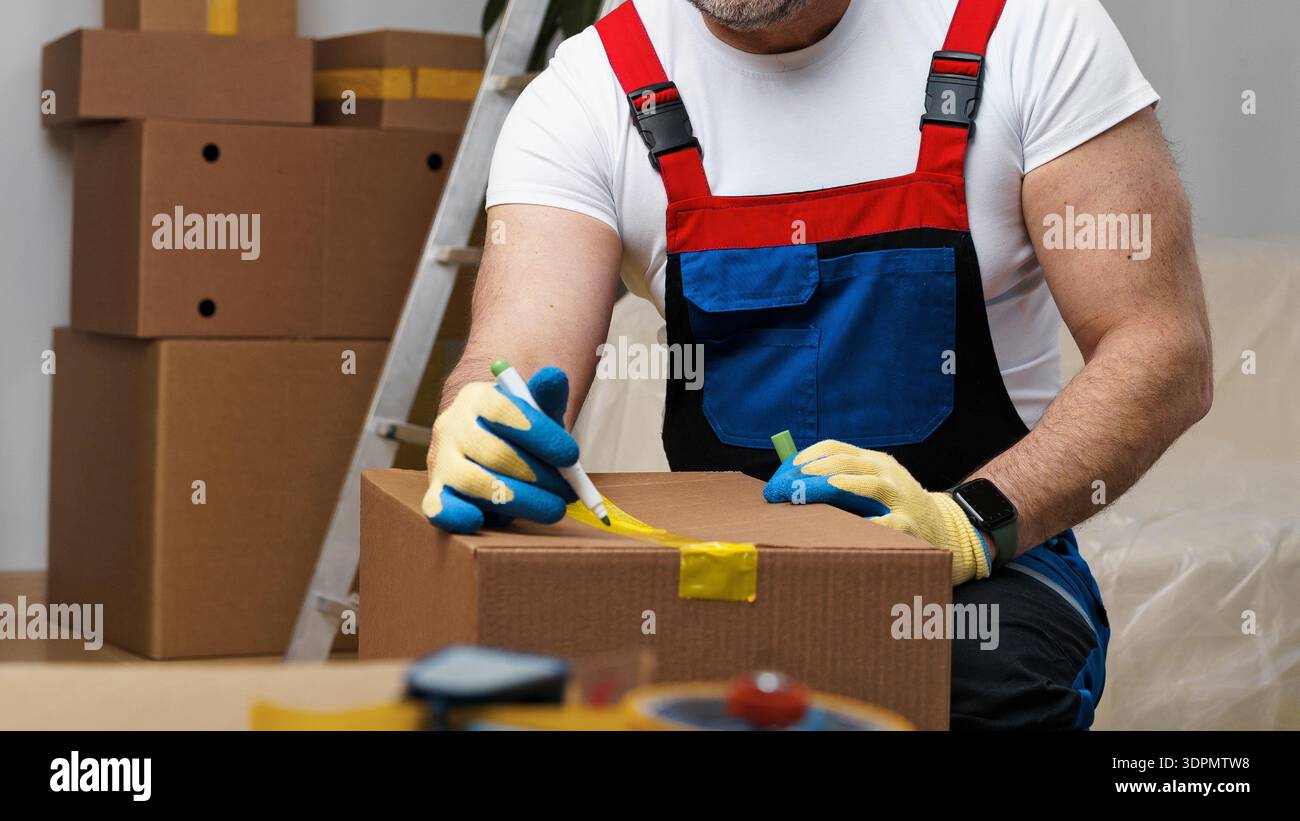 Man-Markierungsboxen für den Transport in einem Raum mit Verpackungsmaterial und Werkzeugen Stockfoto