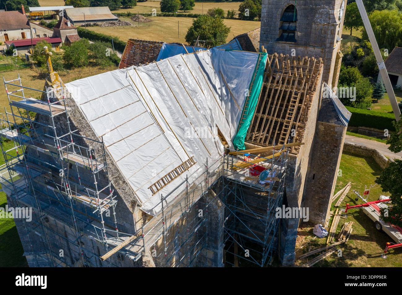 Eglise Saint Martin, Frankreich - 23. Juli 2020: Die Kirche Eglise Saint Martin ist von oben mit Gerüsten, teilweise überdachtem Dach, Baumaterialien und Arbeitern zu sehen, die während der Renovierungsarbeiten in einem ländlichen Gebiet anwesend sind. Stockfoto