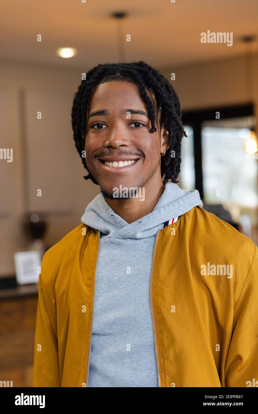 Afroamerikanischer Mann lächelnd und stehend im Café mit Kaffeemaschine, QR-Code-Display-Ständer Stockfoto