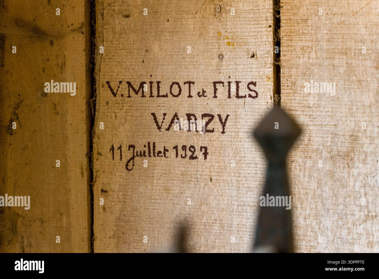 Eglise Saint Martin, Frankreich - 26. Juli 2020: Eine Nahaufnahme eines Holzbretts zeigt eine Inschrift mit der Aufschrift „V. Milot et Fils Varzy 11 Juillet 1927“, wobei ein Teil eines Metallgegenstandes im Vordergrund sichtbar ist. Stockfoto