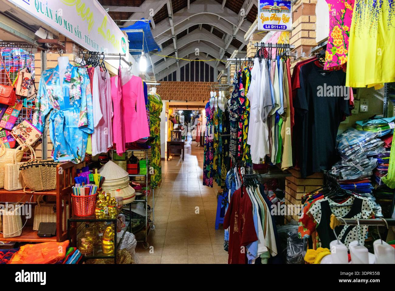 CAN Tho, Vietnam - 19. Januar 2020: Auf dem Nachtmarkt werden Stände mit Kleidung, Hüten, Handtaschen und Souvenirs gesehen. Kleidung und Accessoires werden auf Regalen und Regalen unter künstlicher Beleuchtung ausgestellt. Stockfoto