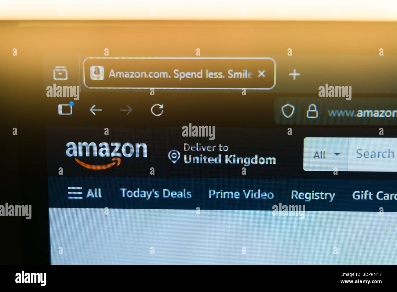 Die Startseite von Amazon wird auf einem Computerbildschirm mit dem offiziellen Logo und der Registerkarte Browser in einem warmen goldenen Licht angezeigt und repräsentiert den globalen E-Commerce, Online s Stockfoto