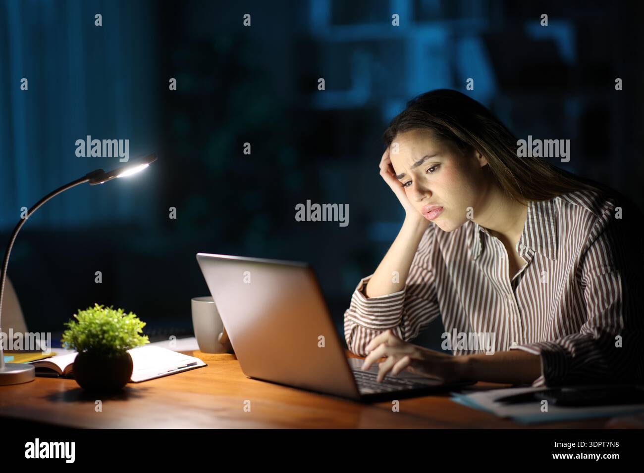 Besorgter Telearbeiter in der Nacht, der online arbeitete und zu Hause einen Laptop suchte Stockfoto