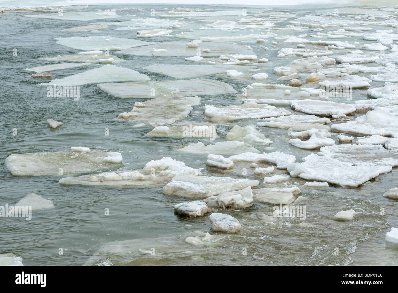 Schwimmendes Meereis und verstreute Eisschollen bilden abstrakte Muster auf kaltem, dunklem Wasser und schaffen einen strukturierten Winterhintergrund Stockfoto