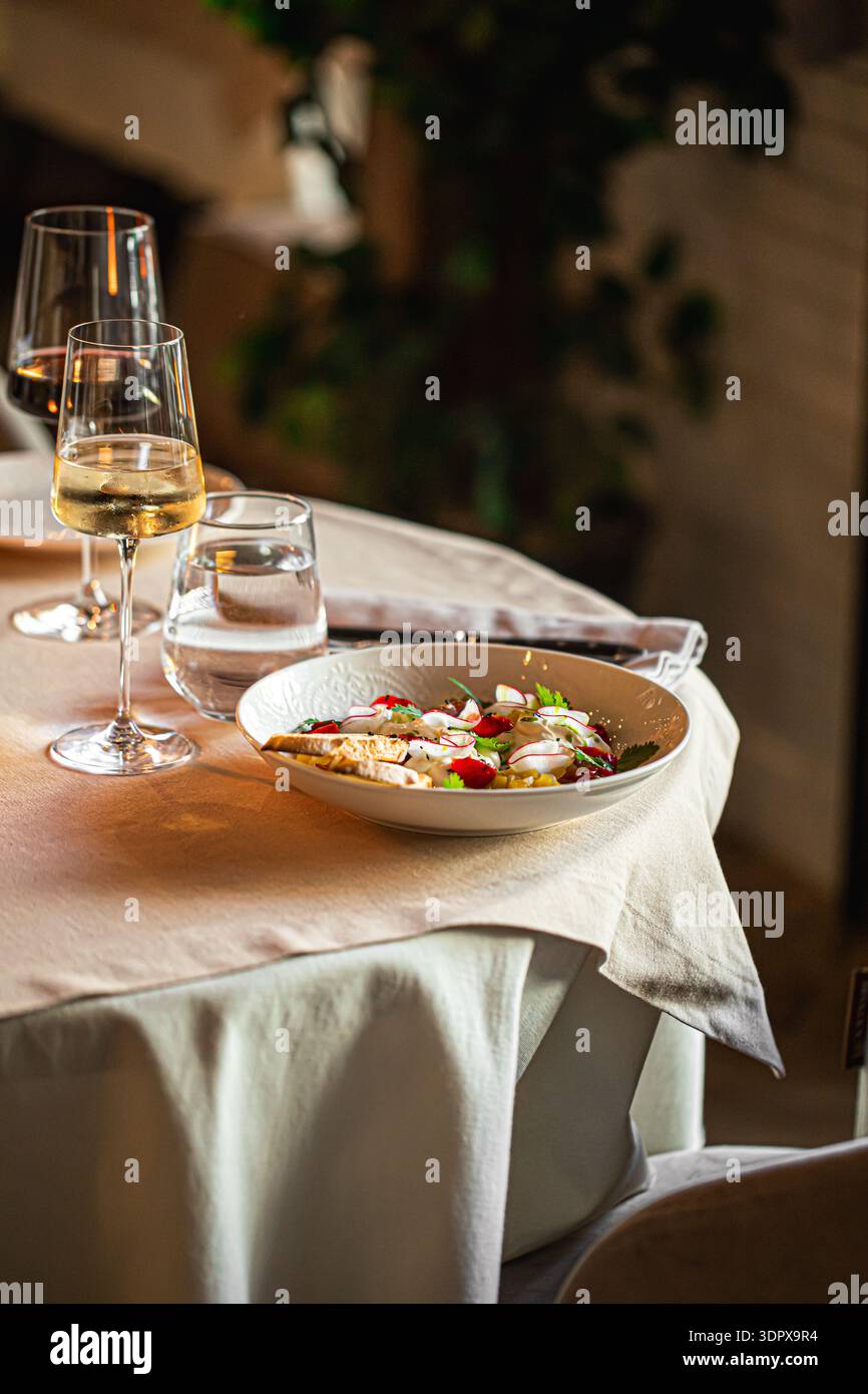 Salat mit Fisch und Wein auf dem Restauranttisch Stockfoto