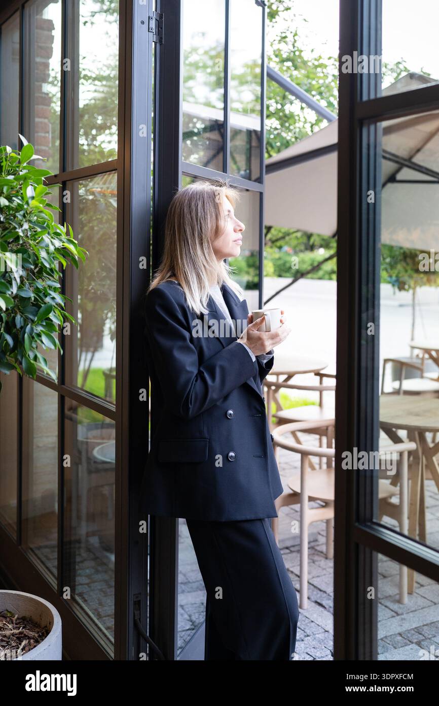 Entspannte, nachdenkliche Geschäftsfrau, Kleinunternehmer, die Kaffee trinkt und über neue Ziele nachdenkt. Stockfoto