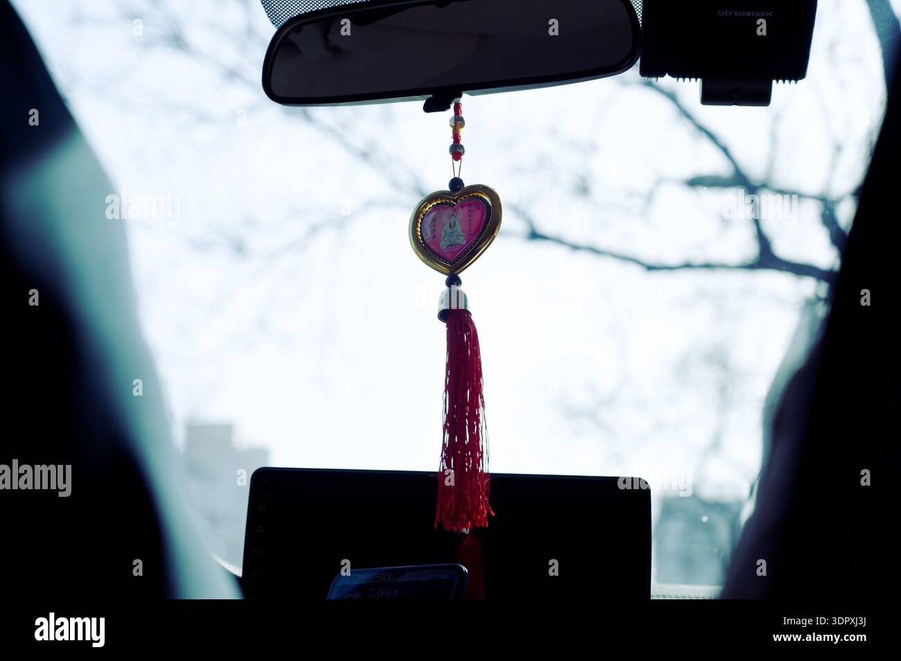 Herzförmiger Quasten-Charme, der während einer Fahrt im Winter an einem Rückspiegel des Taxis hängt Stockfoto