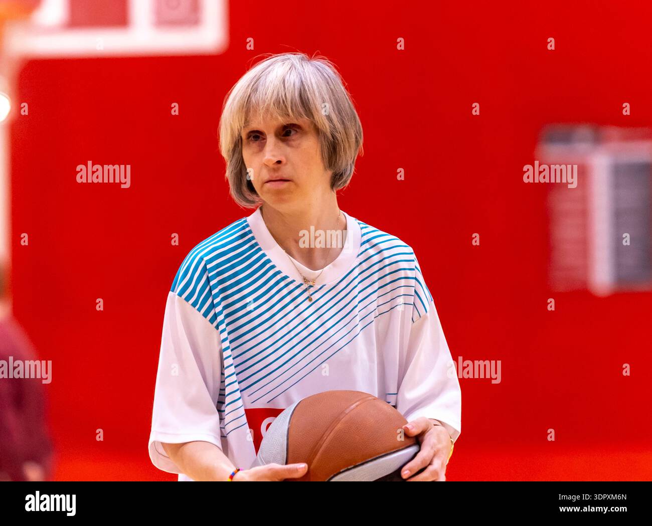 Frau mit intellektueller Behinderung, die beim inklusiven Sporttraining einen Ball hält. Adaptiver Basketball unterstützt Selbstvertrauen, Wohlbefinden, Konzentration und Soci Stockfoto