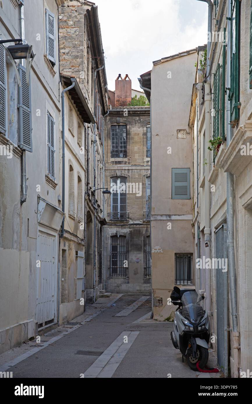 Enge Straße mit historischen Gebäuden, Motorroller und kleinen Mosaiken in der Altstadt von Avignon, Provence-Alpes-Côte d’Azur, Frankreich. Stockfoto