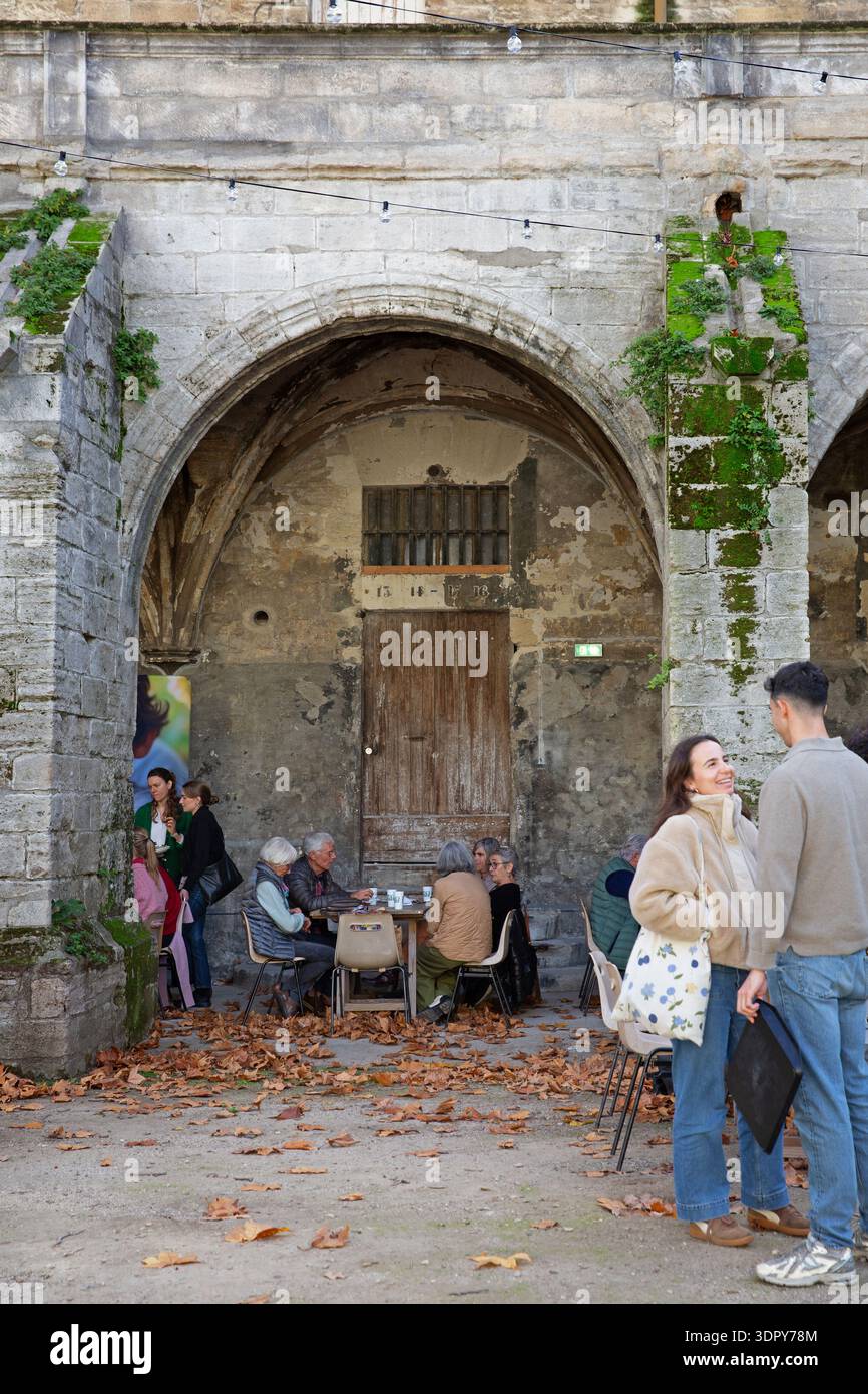 Menschen, die sich unter historischen Steinbögen in Avignon, Provence-Alpes-Côte d’Azur, Südfrankreich, treffen. Stockfoto