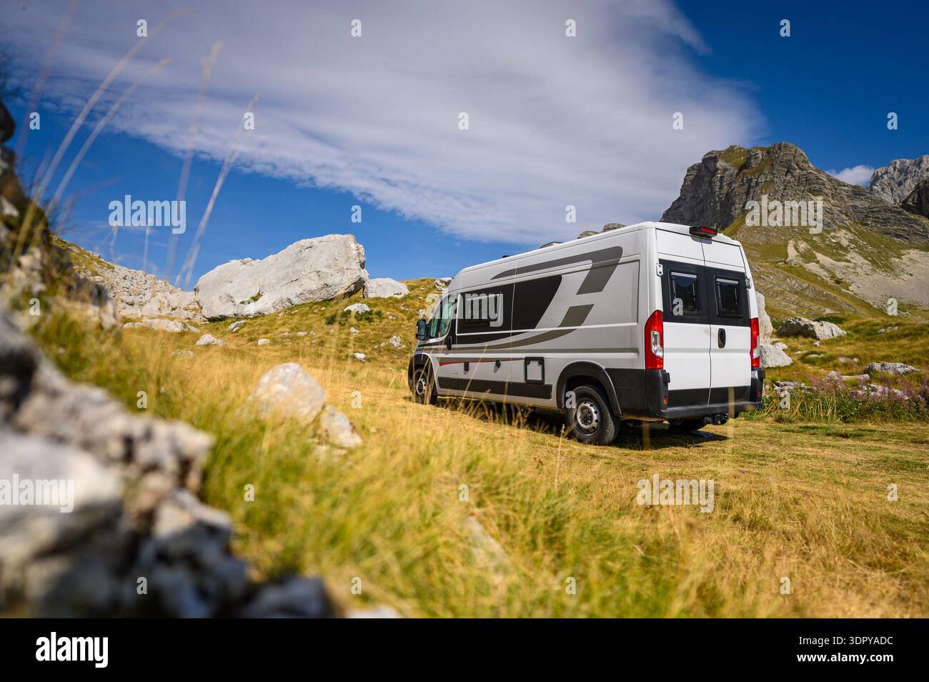 Ein weißer Wohnmobil parkt zwischen großen Kalksteinblöcken am malerischen Sedlo Pass im Durmitor National Park, Montenegro, unter einem hellblauen Himmel Stockfoto