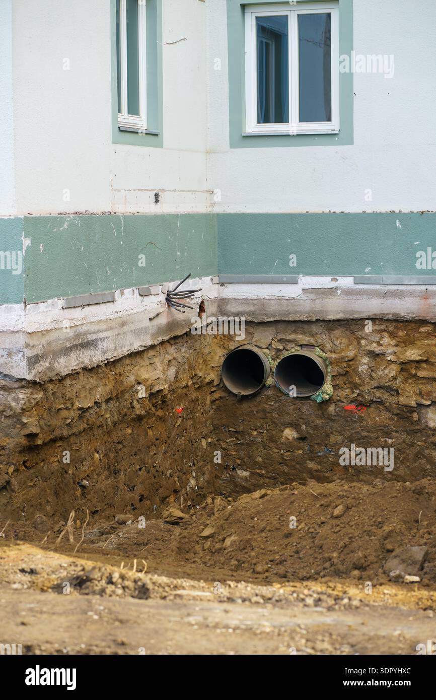 Großer Graben, der neben dem Wohngebäude gegraben wurde und Fundamente und Abflussrohre freilegt. GroundWorks und strukturelle Renovierungen sind im Gange. Stockfoto