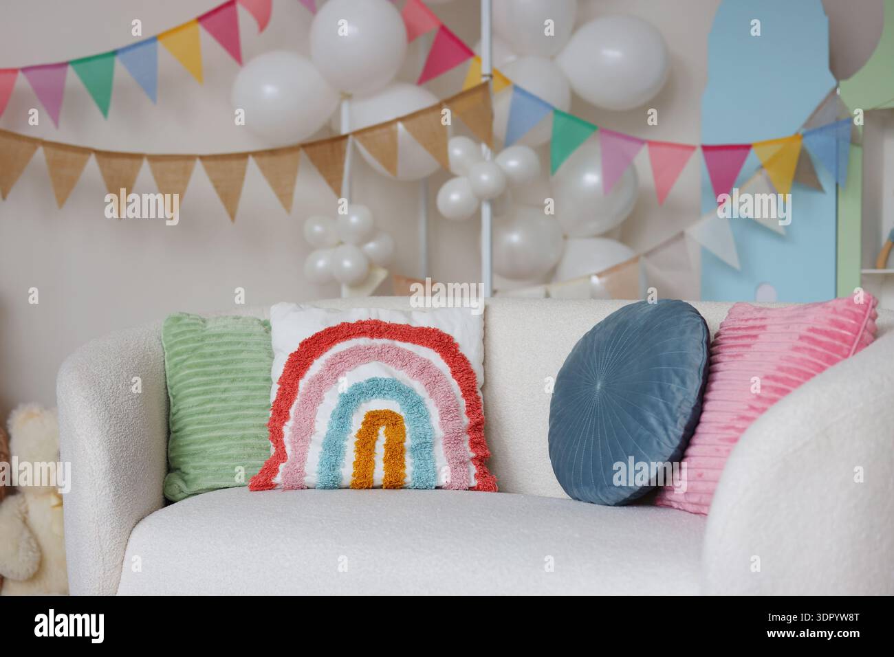 Helles dreieckiges Girlandenbanner, das an einer hellen Wand hängt. Einfaches, fröhliches Partydekor-Konzept mit Kopierraum für Feiertags- oder Geburtstagsthemen. Stockfoto