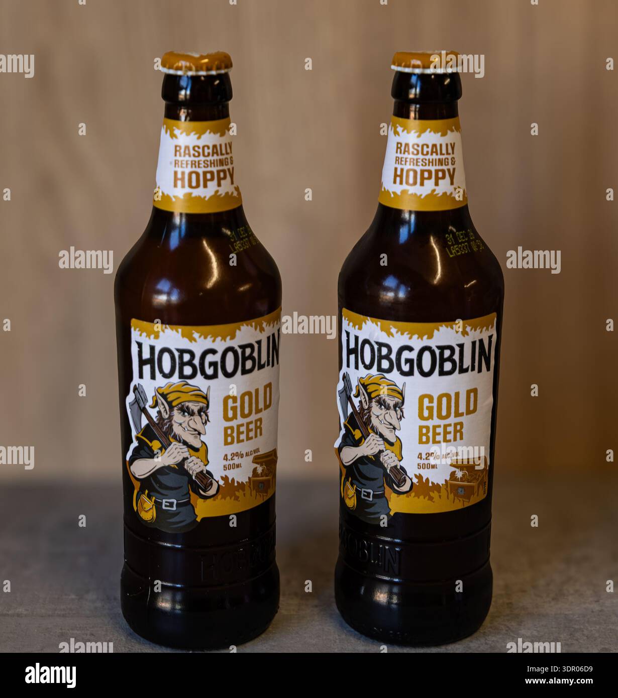 Zwei Flaschen Hobgoblin Gold Bier mit unverwechselbarem Goblin-Etikett auf einer Holzoberfläche Stockfoto