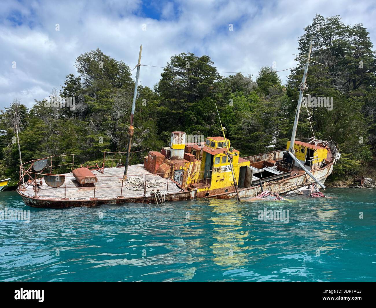 Ein verlassenes Bergbauschiff tauchte teilweise in den See ein, dessen rosthaltige Struktur über der Wasseroberfläche ragt. Altes Wrack als Touristenattraktion Stockfoto
