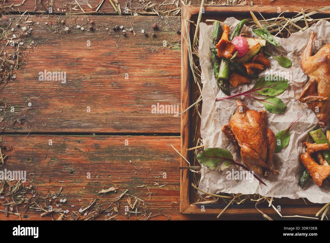 Köstliches Gericht mit gebratenem Huhn, serviert mit Gemüse auf einem Holztisch in einer rustikalen Umgebung Stockfoto