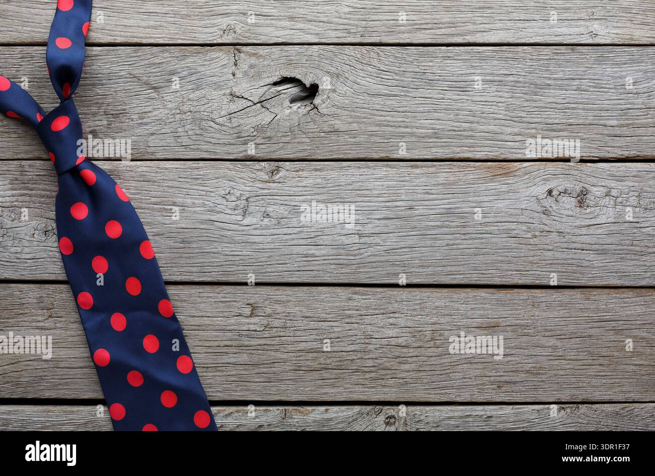 Die Krawatte mit Punktmuster ist während einer lässigen Styling-Session auf Holzoberfläche gewickelt Stockfoto