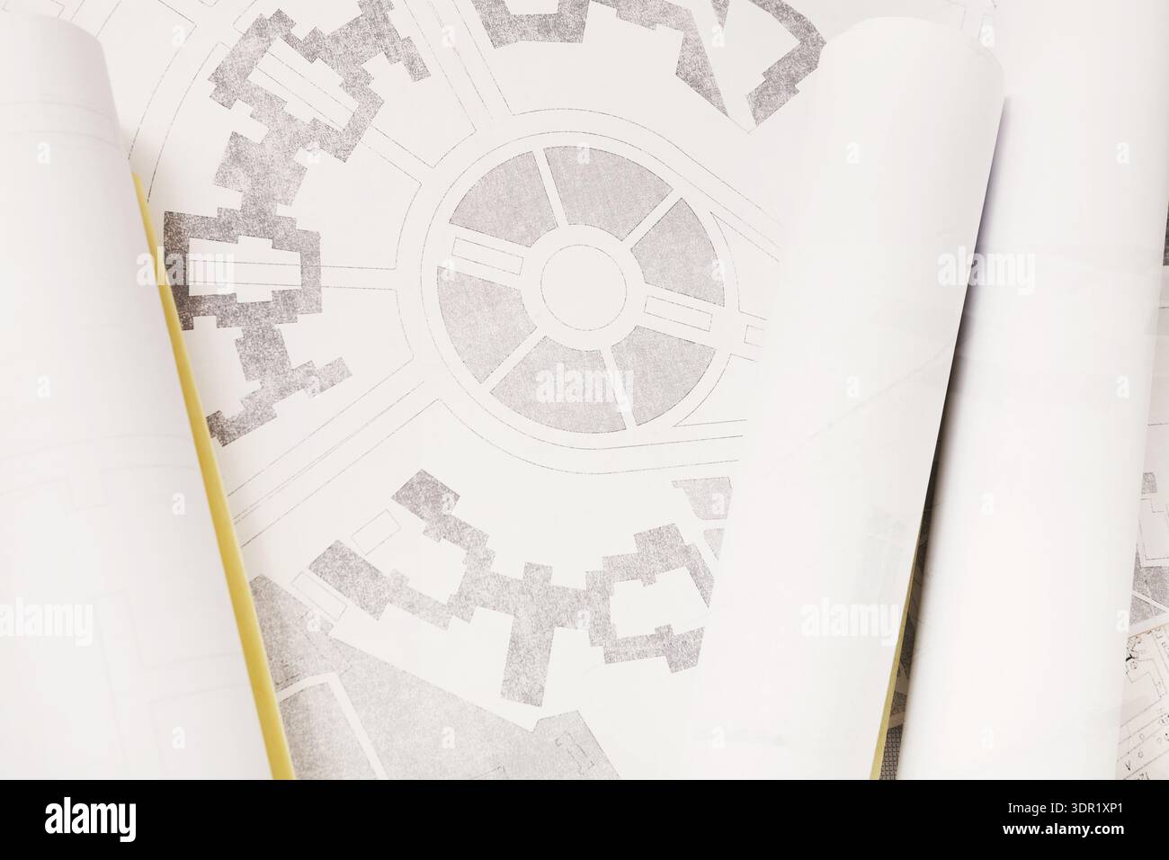 Eine Sammlung von Architekturplänen wird mit mehreren gerollten Dokumenten auf einer flachen Oberfläche angezeigt Stockfoto
