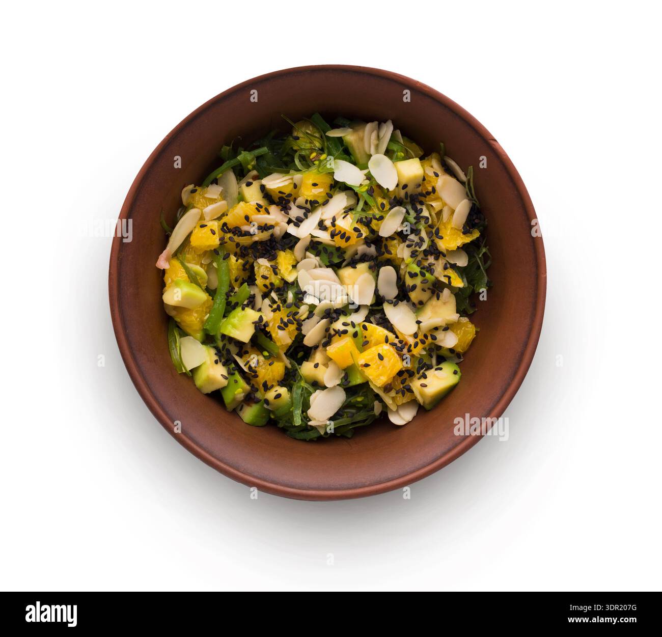 Frischer Salat mit Früchten und Nüssen, serviert in einer braunen Schüssel auf weißem Hintergrund Stockfoto