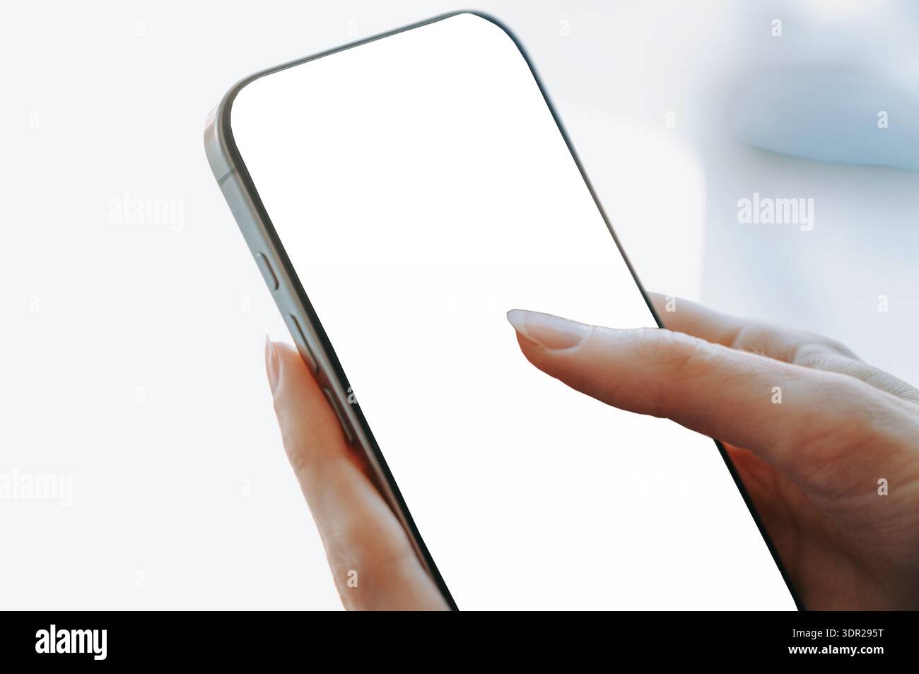 Nahaufnahme einer Frau, die einen leeren weißen Smartphone-Bildschirm in weichem Tageslicht berührt. Aufgeräumtes Modell mit Kopierraum, ideal für das Design mobiler Apps, digital Stockfoto