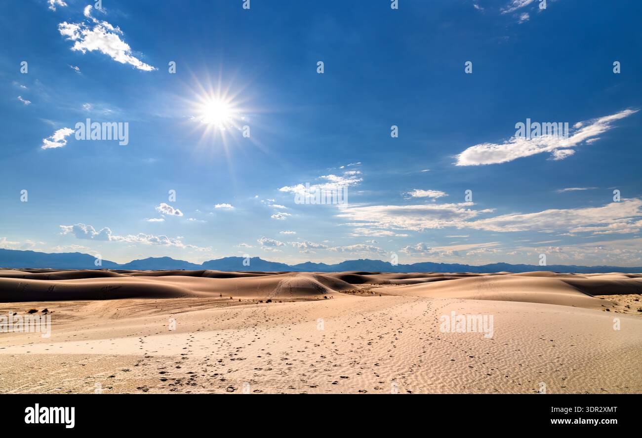 White Sands National Park in New Mexico. Die malerische Landschaft bietet riesige Gipssanddünen mit Fußspuren, die unter einem hellen Sonnenschein in Richtung Berge führen Stockfoto