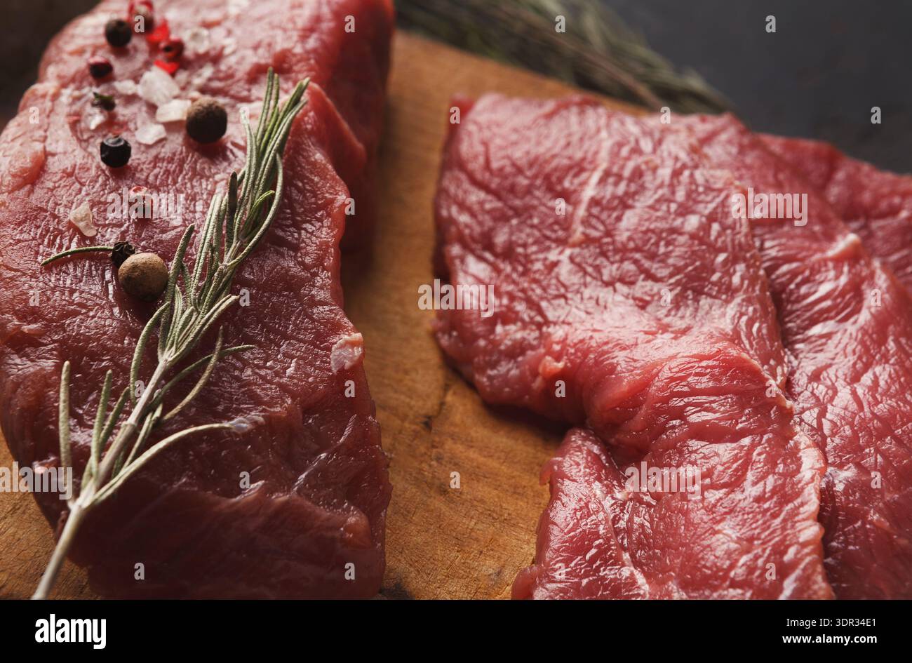 Frisches Rindfleisch mit Kräutern und Gewürzen auf einem hölzernen Schneidebrett Stockfoto