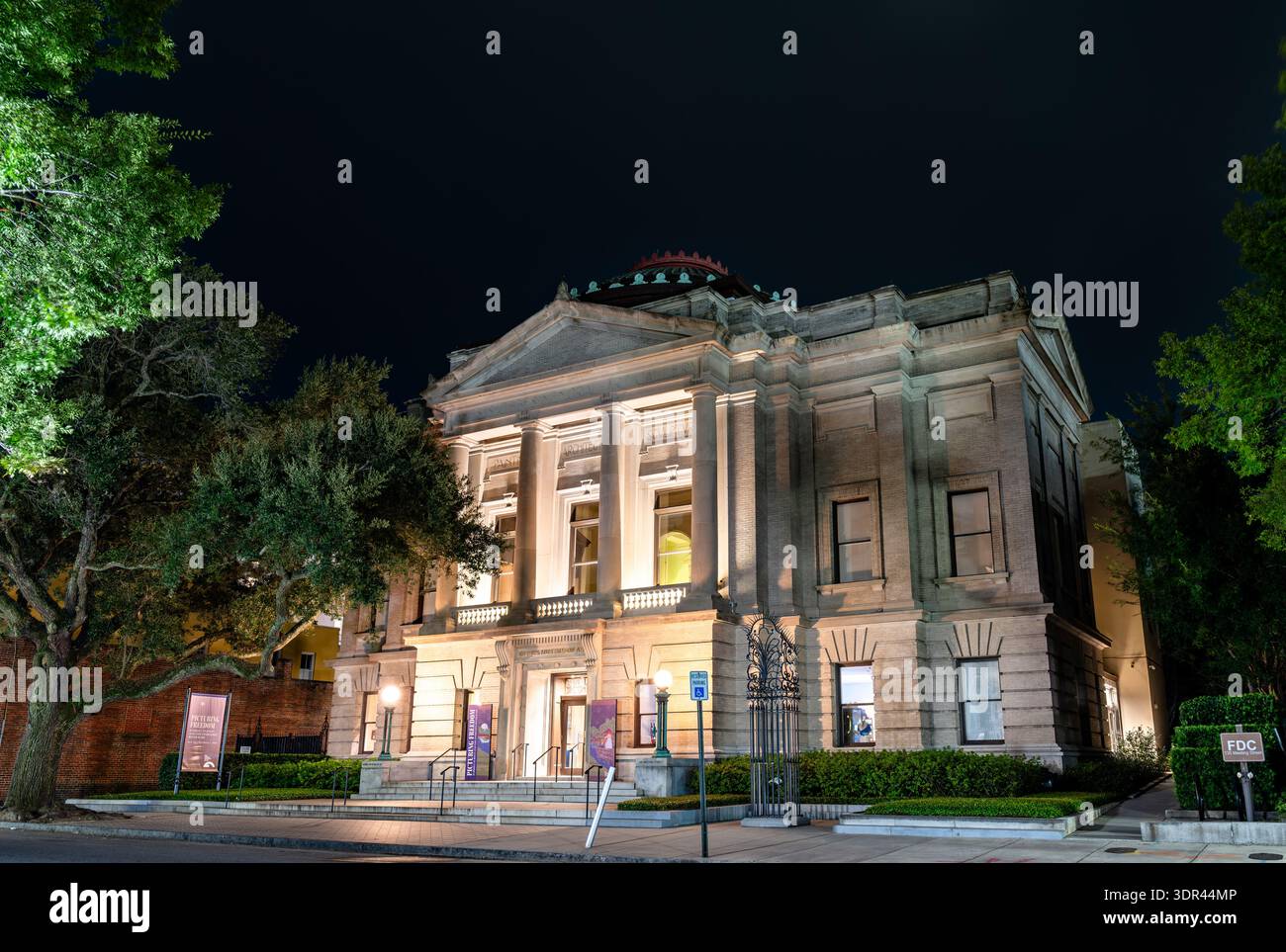 Charleston, South Carolina - 28. August 2025: Gibbes Museum of Art, historisches Beaux-Arts-Gebäude mit einer Steinfassade mit korinthischen Säulen und beleuchteten Stufen bei Nacht auf der Meeting Street Stockfoto